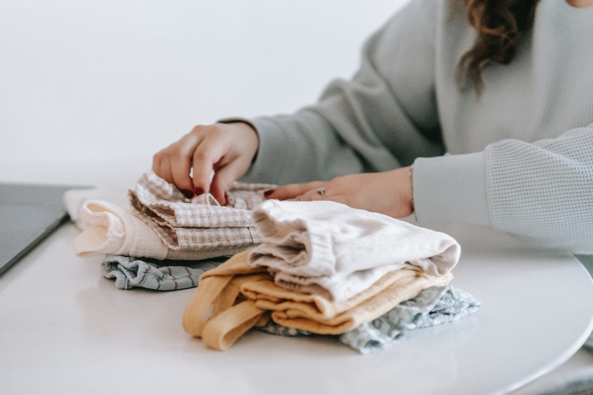 femme home organiser plie vêtements pour enfant sur table blanche