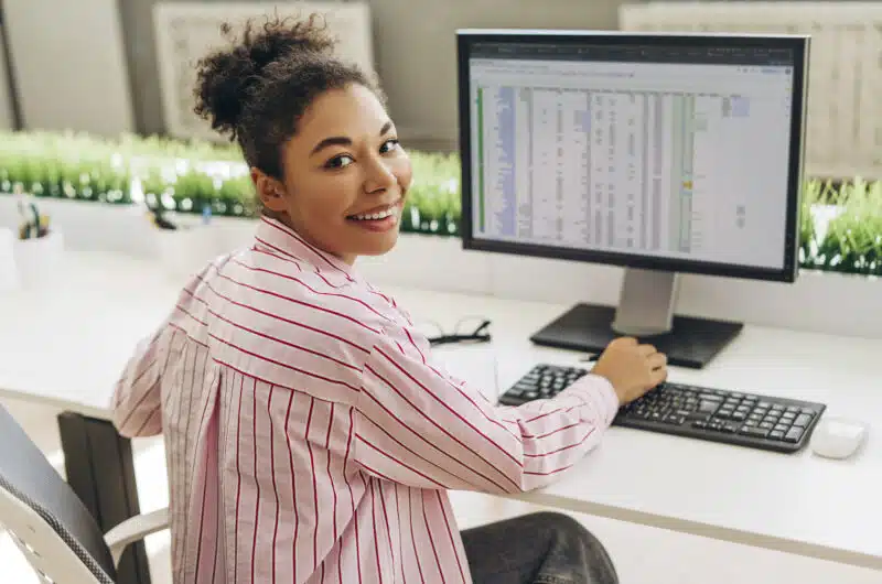 Comptable souriant travaillant avec un tableur sur un ordinateur de bureau